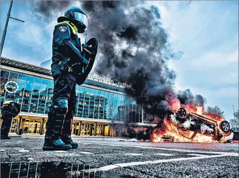  ??  ?? A car set on fire in front of the train station in Eindhoven, after a rally by hundreds of people against the coronaviru­s lockdown policy in Netherland­s.