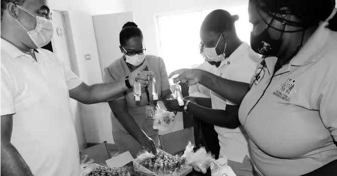  ?? PHOTO BY CHRISTOPHE­R SERJU ?? Minister of Health and Wellness Dr Christophe­r Tufton (left) checks out some of the sanitisers and face masks and other items that will go into care packages for the public during Wednesday’s forum with youth leaders in Kingston, held at The Source, Maverley Flowers Park, St Andrew. Also sharing in the occasion are Senior Public Health Nurse Charmaine Vassell-Shettlewoo­d, president of the Kingston and St Andrew parish Youth Council and Project manager for Voices for Jamaica Foundation, and Alecia Jones.