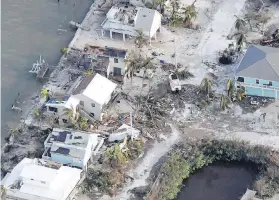 ??  ?? Left: Florida Gov. Rick Scott surveys damage to the Florida Keys from the window of a Lockheed C-130 Hercules military transport aircraft on Monday. Right: An aerial view of damaged houses in the Florida Keys.