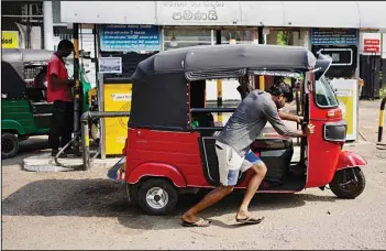  ?? ?? A man pushes his autoricksh­aw to a fuel station in Colombo, Sri Lanka, Wednesday, July 27, 2022. Sri Lanka’s economic crisis has left the nation’s 22 million people struggling with shortages of essentials, including medicine, fuel and food. (AP)