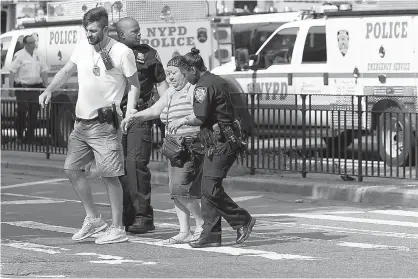  ?? AP Photo/Mary Altaffer ?? Police help people cross the street outside the Bronx Lebanon Hospital on Friday in New York after a gunman opened fire there. The gunman, identified as Dr. Henry Bello, who used to work at the hospital, returned with a rifle hidden under his white lab...