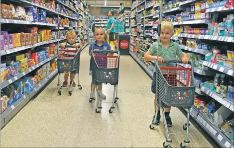  ?? 01_B27coop01 ?? Competitio­n winner Angus Henderson leads the trolley charge with young shoppers Maisie and Jack Picken advancing from the rear.