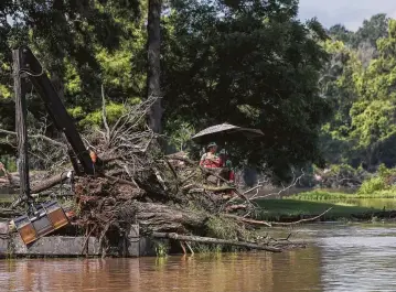  ?? Yi-Chin Lee photos / Houston Chronicle ?? Workers collect limbs and other debris from Lake Houston onto a barge Friday in Huffman. The removal started in May and is a part of Hurricane Harvey debris mitigation.