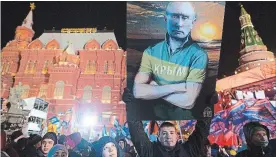  ?? ANDREY RUDAKOV BLOOMBERG ?? Supporters of Vladimir Putin, Russia’s president, hold up a poster during celebratio­ns at a rally near the Kremlin in Moscow.