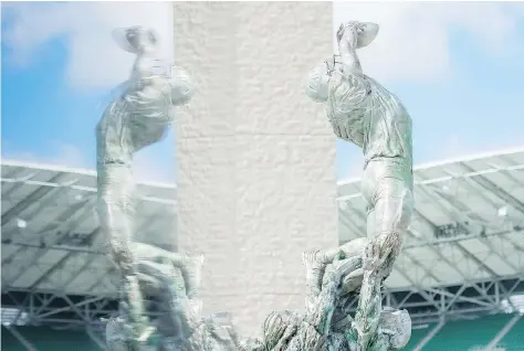  ?? MICHAEL BELL ?? At 18-feet-tall and 2,000 pounds, the new statue outside Mosaic Stadium is sculpted out of white bronze. It shows a football player making a catch, assisted by Rider fans. The statue is captured above, reflected in a fan wall at its unveiling.