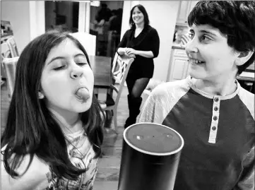  ?? — Washington Post photo by Bill O’Leary ?? Laura Labovich (background) and her children Asher (right), 13, and Emerson, 10, with the family “Alexa”, an artificial intelligen­ce device in Bethesda.