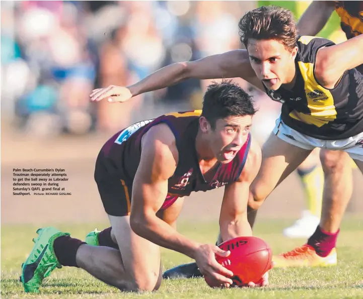  ?? Picture: RICHARD GOSLING ?? Palm Beach-Currumbin’s Dylan Troutman desperatel­y attempts to get the ball away as Labrador defenders swoop in during Saturday’s QAFL grand final at Southport.