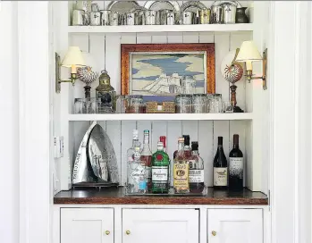  ??  ?? Some of the family’s sailing awards and trophies are displayed on a built-in bar, which stands out against the fresh, crisp white walls designer Amy Zantzinger chose for the space in this Maryland retreat.