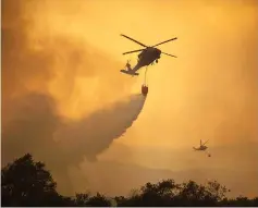  ??  ?? National Guard helicopter­s make water drop as the Thomas Fire approaches the Lake Casitas area near Ojai, California. — AFP photo