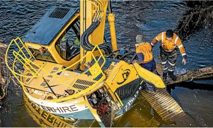  ?? PHOTOS: VANESSA LAURIE/STUFF ?? A yellow digger got stuck in the Manganui River during an attempt to pull a tree out.