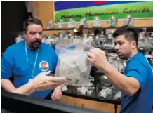  ?? Theo Stroomer/AFP/Getty Images ?? Sam Walsh, left, and David Martinez set up marijuana products as the 3-D Denver Discrete Dispensary prepares to open Jan. 1 in Denver.