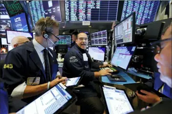  ?? RICHARD DREW — THE ASSOCIATED PRESS ?? Specialist Anthony Matesic, center, works with traders at his post on the floor of the New York Stock Exchange, Wednesday.