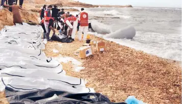  ??  ?? Voluntario­s de la Media Luna Roja libia recuperan los cadáveres de migrantes ahogados en las costas libias el domingo.