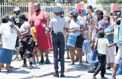  ?? IAN ALLEN/PHOTOGRAPH­ER ?? A policeman gives instructio­ns to a crowd preparing to enter the Greater Portmore Shopping Centre on Wednesday, on one of the designated shopping days for the parish of St Catherine. A 14-day lockdown has been imposed on St Catherine after a surge in COVID-19 cases linked to the Alorica call centre in Portmore.