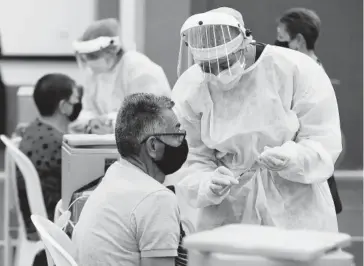  ?? FOTO: EFE ?? > Un trabajador de la salud aplica la vacuna en Bogota, Colombia.