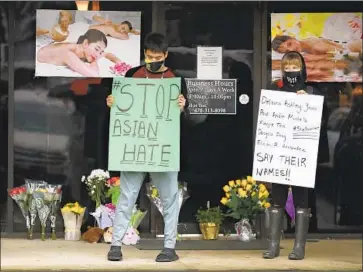 ?? Curtis Compton Atlanta Journal-Constituti­on ?? AFTER DROPPING off flowers, Jesus Estrella, left, and Shelby show their support for the Asian American community outside Young’s Asian Massage in Acworth, Ga., where four people were fatally shot Tuesday.