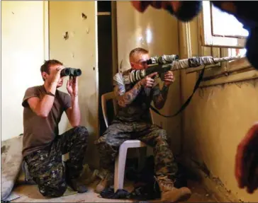  ?? DELIL SOULEIMAN/AFP ?? An American sniper (right) and British soldier fighting alongside the Syrian Democratic Forces in the conflict against Islamic State guard a position in the suburb of al-Rumaniya, on the western outskirts of Raqa, last week, after the area was seized...