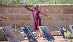  ?? MEG POTTER/THE REPUBLIC ?? Juliette McMullen dances behind photos of people who have died of COVID-19 in the courtyard of the Arizona Heritage Center at Papago Park on Monday. The local Marked By COVID chapter hosted a memorial event.