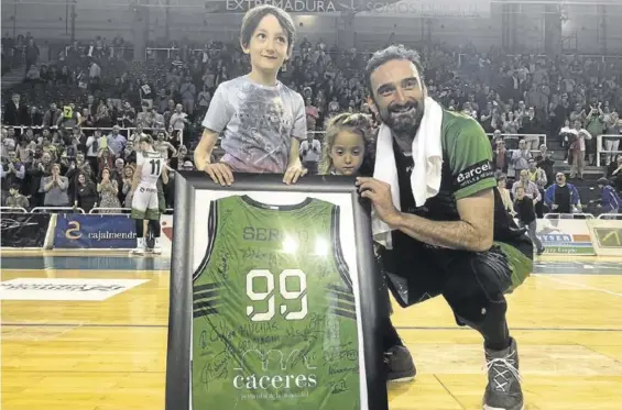  ?? CACRES BASKET ?? Sergio Pérez, junto a sus hijos, con una camiseta del Cáceres firmada por todos sus compañeros, ayer al acabar su último partido.