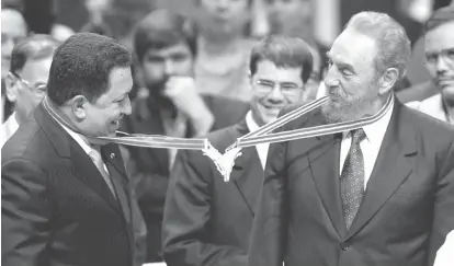  ??  ?? Venezuela’s President Hugo Chavez, left, and his Cuban counterpar­t Fidel Castro joke after joining their medallions, given by medical graduates, at Havana’s Karl Marx theatre. — Reuters