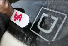  ?? Gene J. Puskar/Associated Press ?? A Lyft logo is installed on a car next to an Uber sticker in Pittsburgh in January 2018.