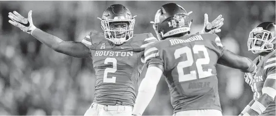  ?? Elizabeth Conley / Staff photograph­er ?? Deontay Anderson, left, shows off his wingspan after intercepti­ng a pass for Houston in the second half against Tulsa at TDECU Stadium on Thursday night.