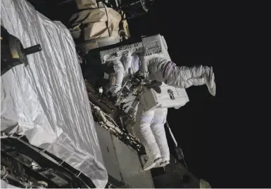  ?? NASA ?? Kate Rubins (foreground) and Victor Glover install solar array modificati­on kits on the space station Feb. 28.