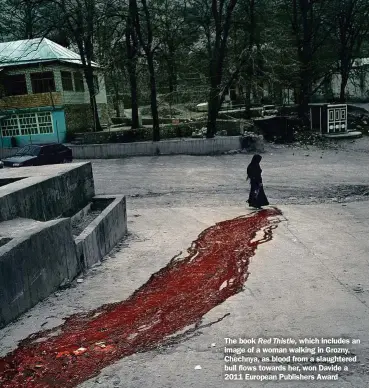  ??  ?? The book Red Thistle, which includes an image of a woman walking in Grozny, Chechnya, as blood from a slaughtere­d bull flows towards her, won Davide a 2011 European Publishers Award