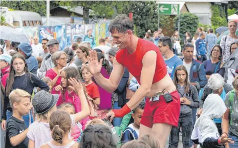  ?? FOTO: HARALD RUPPERT ?? Hier löst sich ein Stau auf: Ein Straßenkün­stler bekommt beim Kulturufer vor dem großen Zelt gutes Geld für eine gute Show.