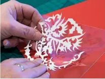  ??  ?? A steady hand is required as Kirstin takes care not to cut into the motifs she wants to reveal. The delicate paper cutting is carefully placed on a piece of acetate used to separate layers of paper and achieve a floating effect.