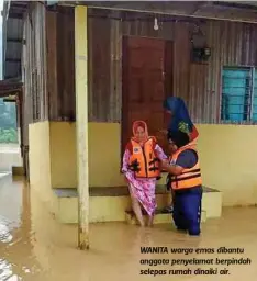  ??  ?? WANITA warga emas dibantu anggota penyelamat berpindah selepas rumah dinaiki air.