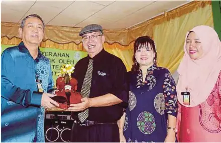  ?? [FOTOMALAIR­OSMAHTUAH/BH] ?? Suria (kiri) menerima sumbangan biola daripada Peter Chua di Dewan Bestari, Penjara Pusat Kota Kinabalu semalam.