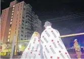  ?? AMY BETH BENNETT/STAFF PHOTOGRAPH­ER ?? Richard Markey and his fiancee look back at the Intracoast­al Towers, a 15-story condo building. The fire started on the seventh floor.