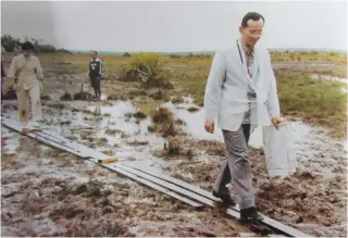  ??  ?? The Thai King walking through a muddy field.