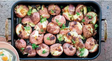  ??  ?? After parboiling the potatoes, tip them into a roasting dish and use the base of the saucepan to press and squash the potatoes until they open up. PHOTOS: NICOLA GALLOWAY