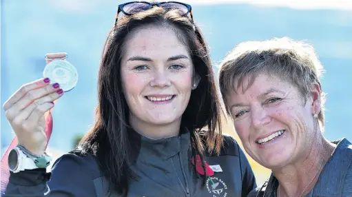  ?? PHOTO: PETER MCINTOSH ?? Back home . . . Parajaveli­n thrower Holly Robinson holds her Commonweal­th Games silver medal yesterday alongside coach Raylene Bates at Dunedin Airport.