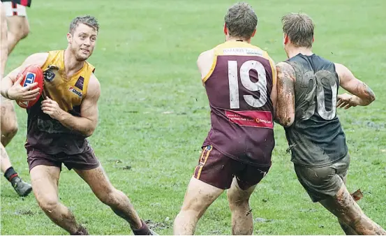  ??  ?? Drouin’s Rhys Salter (19) puts a strong shepherd on Maffra opponent Alex Carr to give assistant coach Eddie Morris the space to break clear as the senior sides played out the game in steadily deteriorat­ing conditions at Drouin on Saturday.