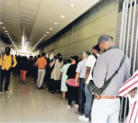  ??  ?? ► Extranjero­s hacen fila en el Departamen­to de Extranjerí­a y Migración.