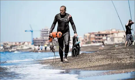  ?? ANDREW MEDICHINI/AP ?? Fisherman Federico Burresi walks along the beach Saturday in Ladispoli, a coastal town outside of Rome.