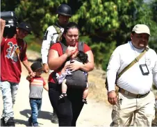  ?? — AFP photo ?? A family of Central American migrants are escorted by members of the Mexican National Guard and officers of the Migration Institute after being detained in Ciudad Hidalgo, Chiapas State, Mexico.