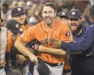  ?? Fred Thornhill / Associated Press ?? Justin Verlander of the Astros is mobbed by teammates after pitching a nohitter against the Blue Jays in Toronto on Sunday.