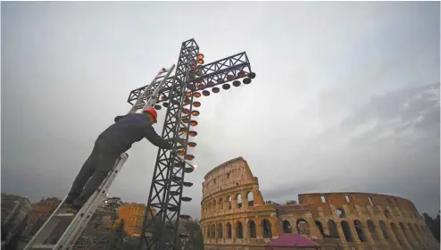  ?? FILIPPO MONTEFORTE AGENCE FRANCE- PRESSE ?? Un ouvrier illumine une croix avant une procession de Pâques menée par le pape François à Rome. Peut-on espérer quand on ne croit plus ou sommesnous voués à la désespéran­ce ?