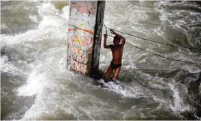  ??  ?? MANILA: A boy plays in a swollen creek under a bridge. — AFP