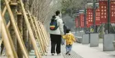  ?? QILAI SHEN/THE NEW YORK TIMES ?? A woman walks with her child in Shanghai. China’s population fell last year for the first time since a national famine in the 1960s.