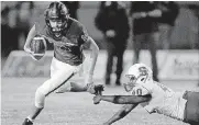  ?? [PHOTO BY SARAH PHIPPS, THE OKLAHOMAN] ?? Norman North quarterbac­k Jacob Switzer, left, escapes a tackle by Stillwater’s Eyuel Abame during Thursday night’s high school game in Norman.