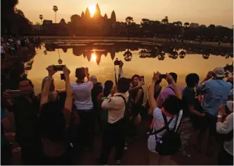  ?? AP photos ?? Tourists take photos of the sunrise at the Angkor Wat on the northern outskirts of Siem Reap, Cambodia.—