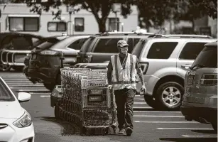  ?? Bloomberg file photo ?? A Walmart employee pulls shopping carts in Lakewood, Calif., last July. Walmart’s CEO said new wage increases mean about half of Walmart’s U.S. workers would earn at least $15 an hour.