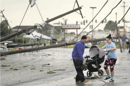  ?? Charlie Riedel / Associated Press ?? Ray Arellana and Jessica Rodgers carry Rodgers’ sister Sophia after a tornado tore apart buildings in Jefferson City, Mo.