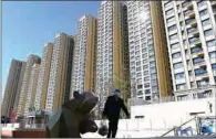  ?? (AFP) ?? A man walks in front of a housing complex by Chinese property developer Evergrande in Beijing on Thursday.