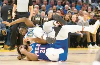  ?? D. ROSS CAMERON/AP ?? Warriors forward Draymond Green falls over 76ers center Joel Embiid on an offensive foul by Embiid in the first half on Tuesday.